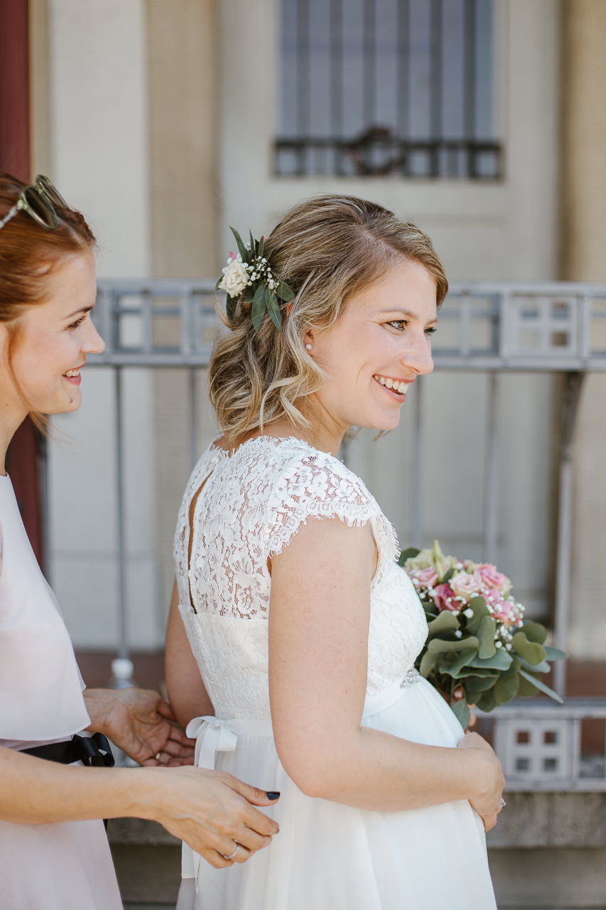 Die Schleife sitzt. Trauzeugin und Braut vor dem ersten Zusammentreffen mit dem Bräutigam. Strahlendes Brautpaar im Garten des Wöschhüsli in Regensdorf. Dieser sorgt für tolle Bilder beim Brautpaarshooting. Bild: Stephanie Wittmer Fotografie