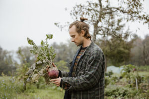 Lucas von Permaterra begutachtet eine Raebe. Business Reportage fotografiert von Stephanie Wittmer für den Schweizer Garten.