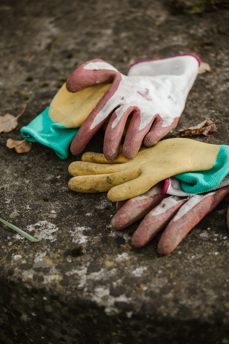 Arbeitsdetail: Abgelegte Gartenhandschuhe auf einem Stein auf dem Biobetrieb.