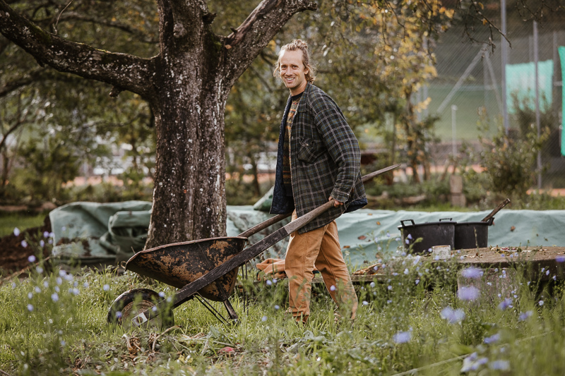 Lucas ist unterwegs mit der Schubkarre im herbstlichen Permakulturgarten