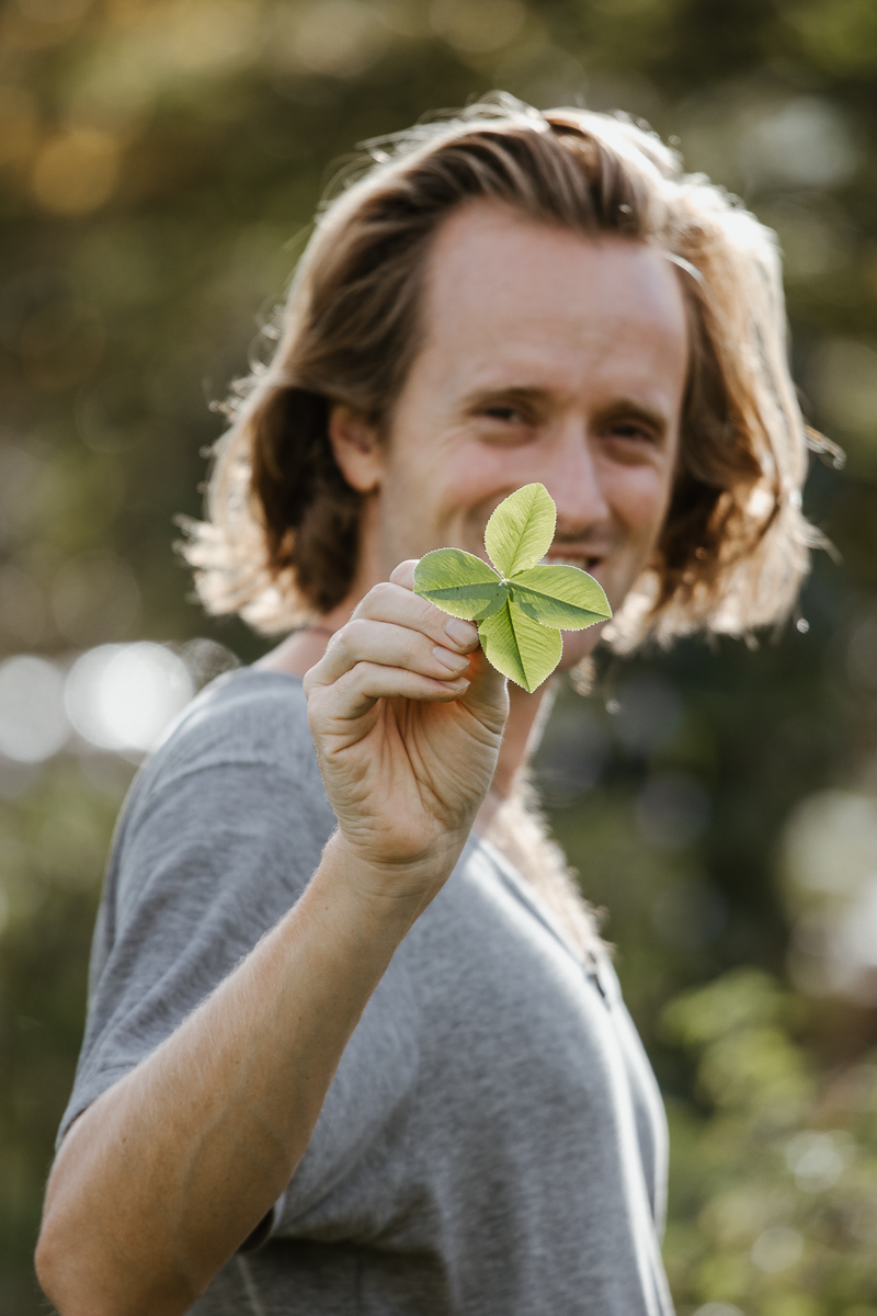 Lucas hält ein vierblättriges Kleeblatt in die Kamera. Authentisches Reportage-Porträt.