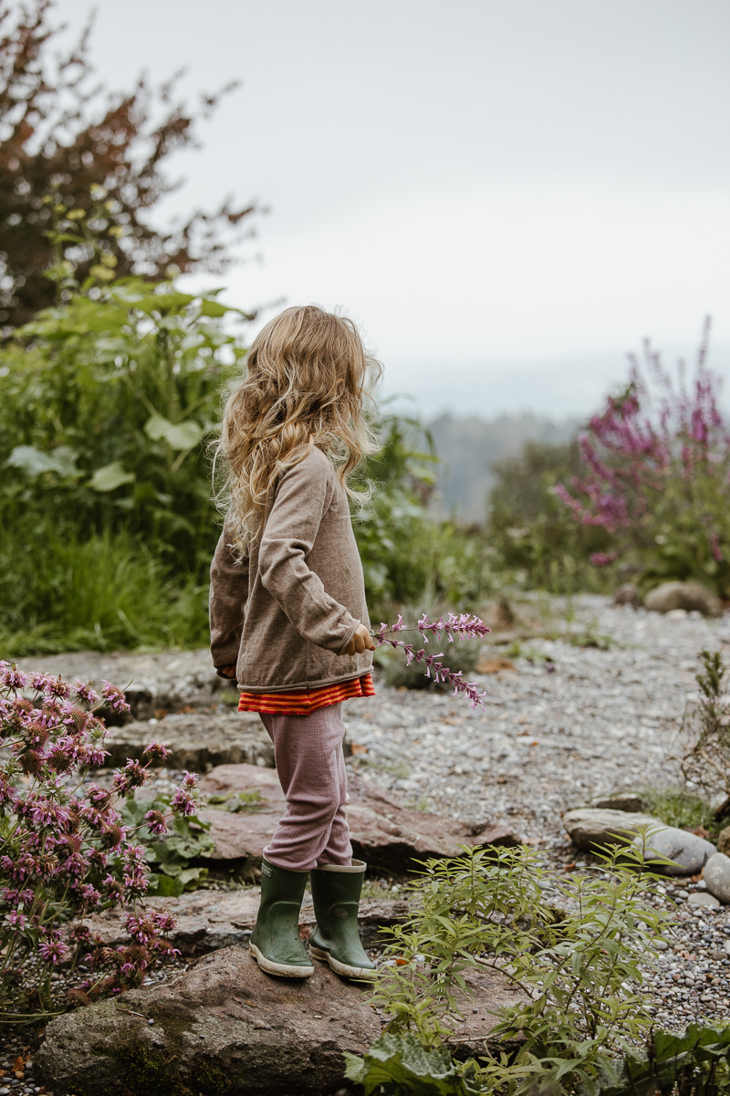 Die Tochter in Gummistiefeln im Garten.