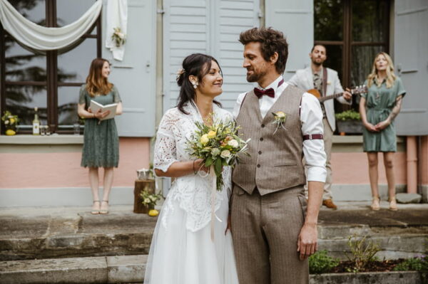 Brautpaar nach der Freien Trauung im Schlössli Utenberg. Im Hintergrund die Zeremonienleiterung, sowie Gitarrist und Sängerin.