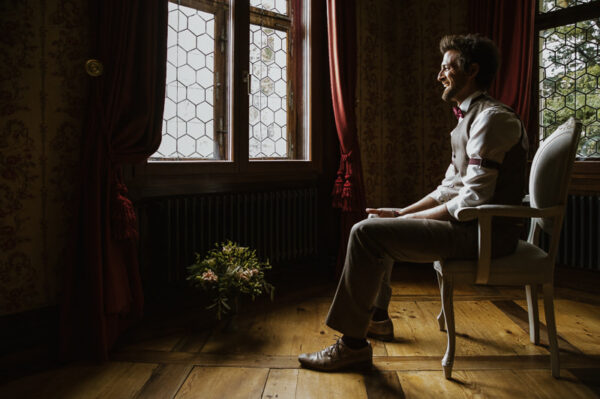 Bräutigam sitzt im Rosenzimmer – Getting Ready Schlössli Utenberg Luzern